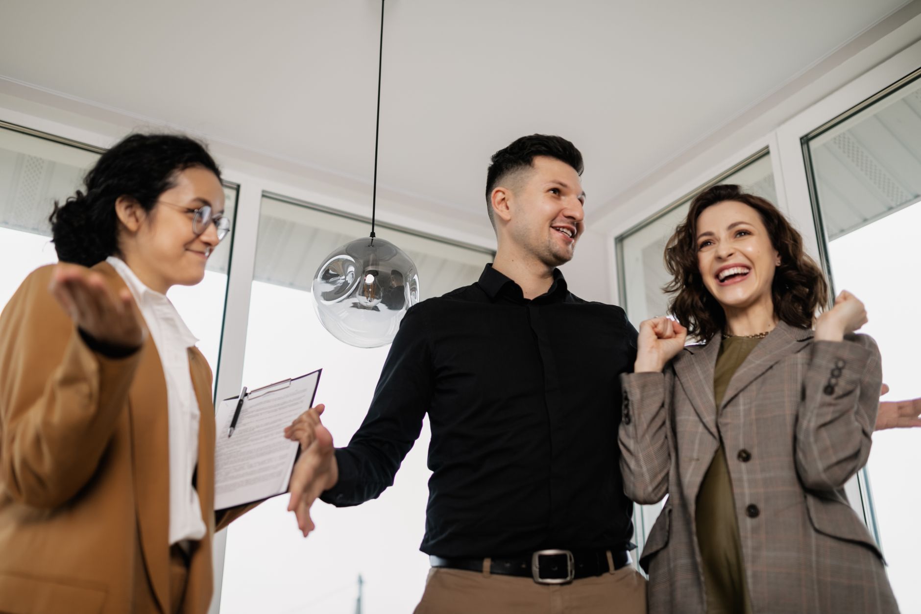 confident real estate agent showing keys to a happy couple