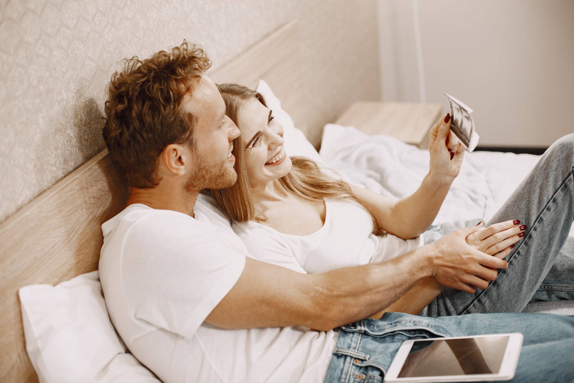 happy young couple looking at house plans on a tablet, smiling